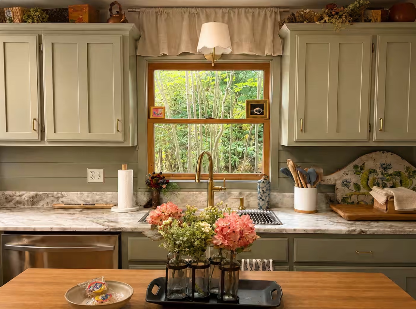 Kitchen with sage cabinetry and marble counters